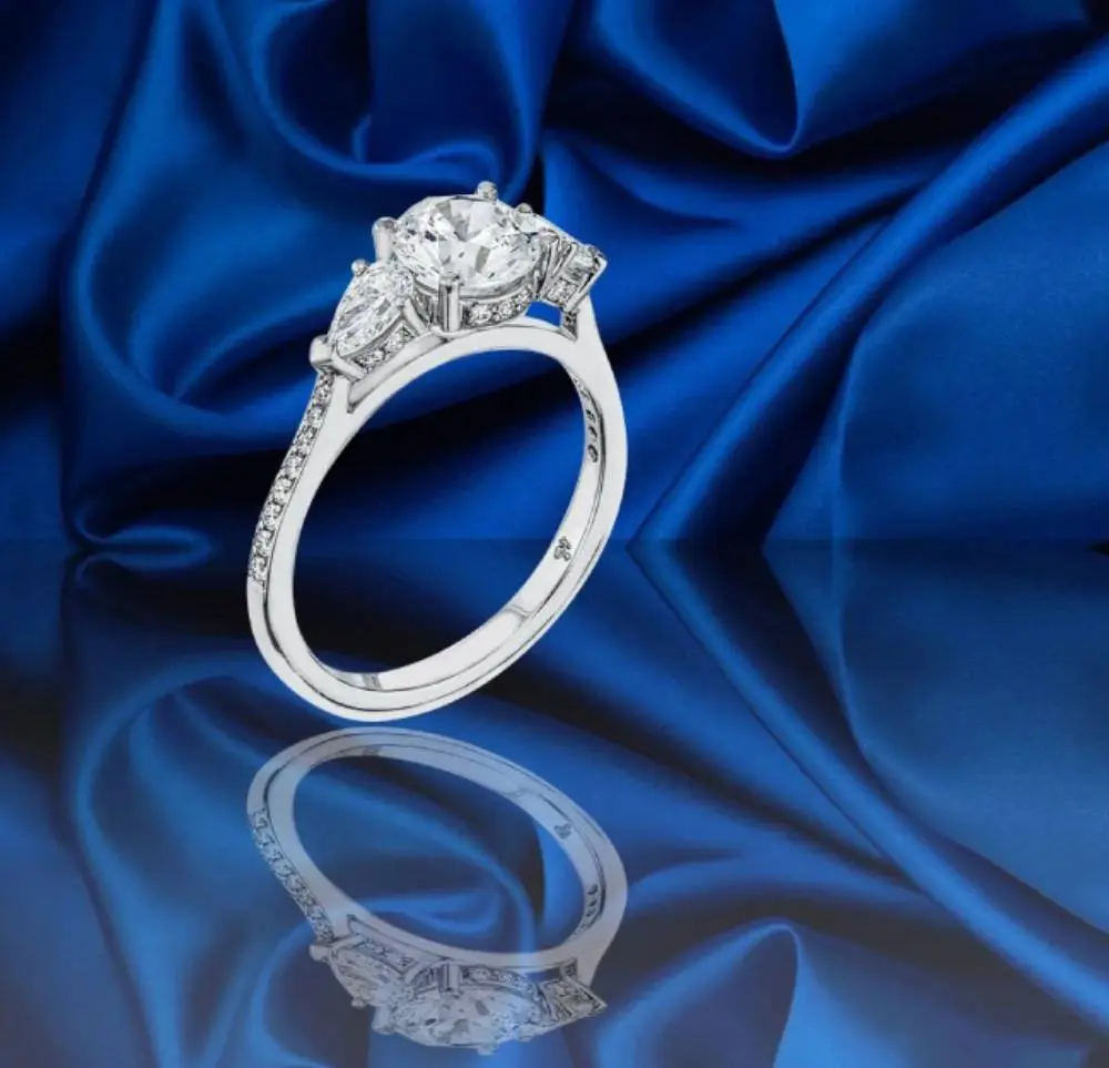 A diamond ring sitting on top of a blue cloth.