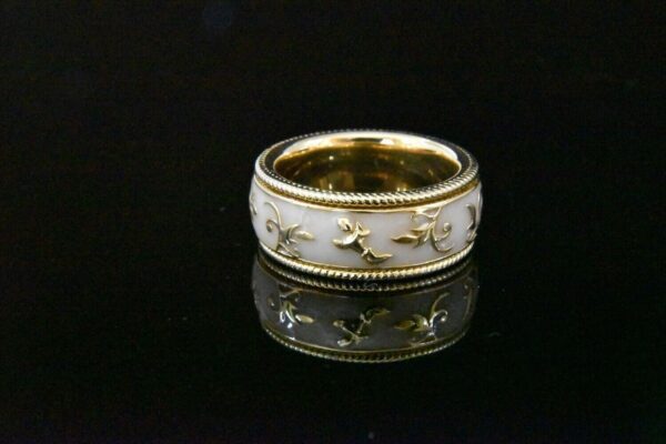 Gold ring with white enamel floral design.