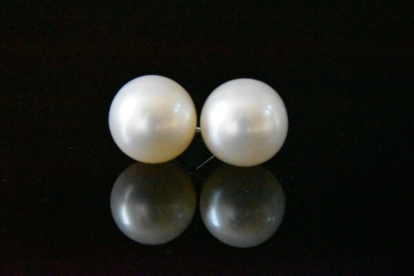 Pair of pearl earrings on black background.