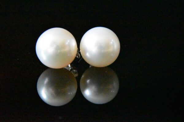 Pair of pearl earrings on black background.