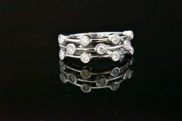 Triple-row diamond ring on black background.