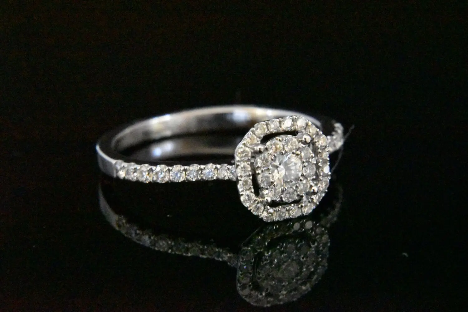 Diamond halo engagement ring on black.