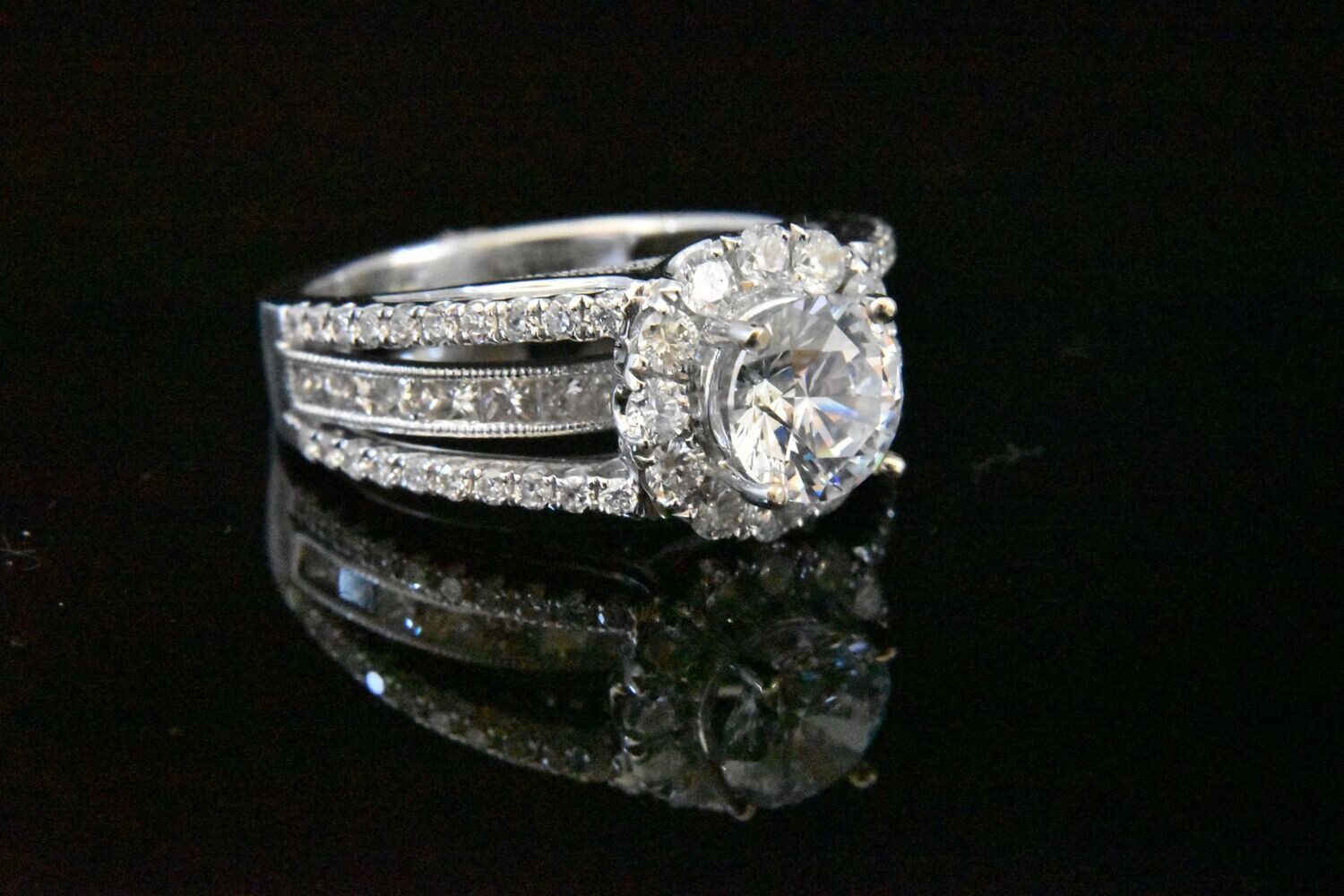 Diamond halo engagement ring on black.