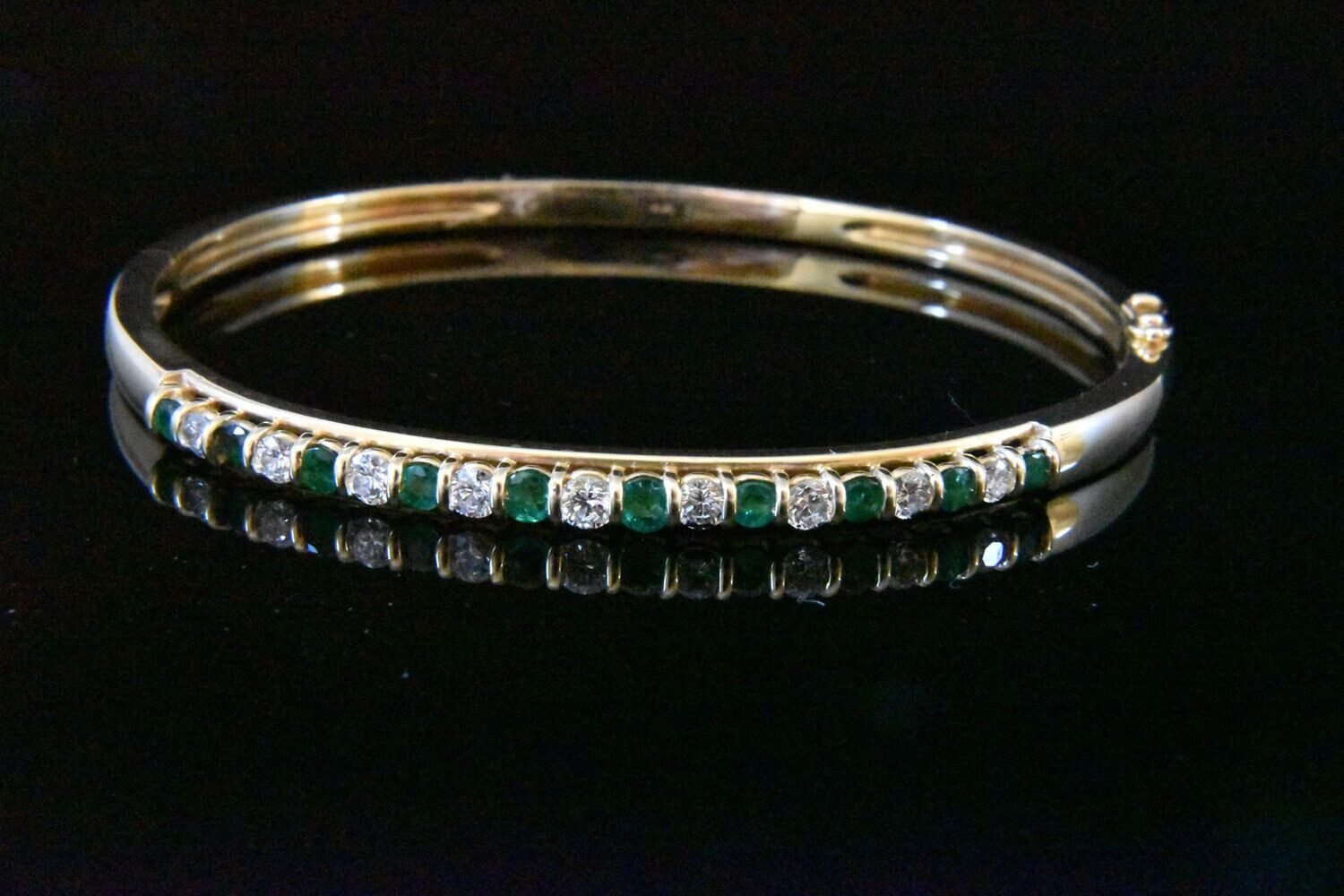 Gold bangle with emeralds and diamonds.