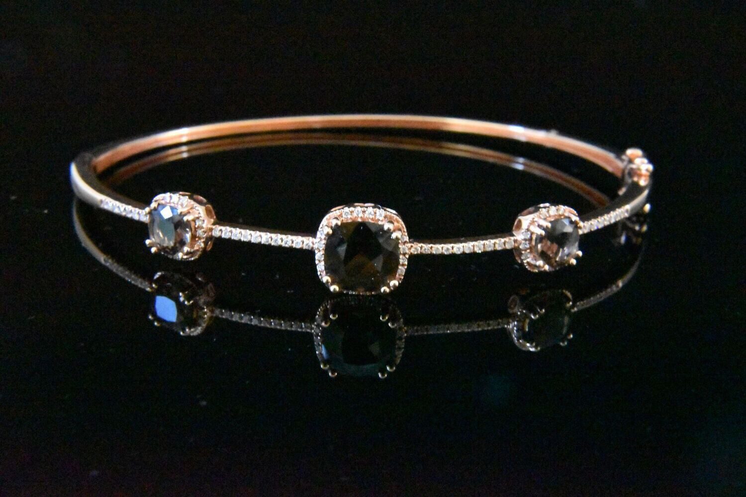 Rose gold bangle with three black diamonds.