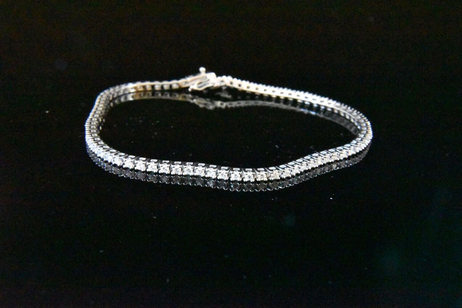 Diamond tennis bracelet on black background.