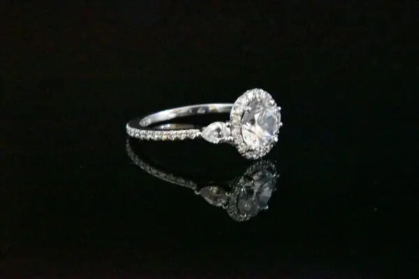 Diamond halo engagement ring on black.