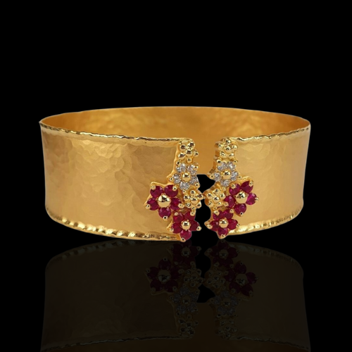 Gold cuff bracelet with ruby and diamond flowers.