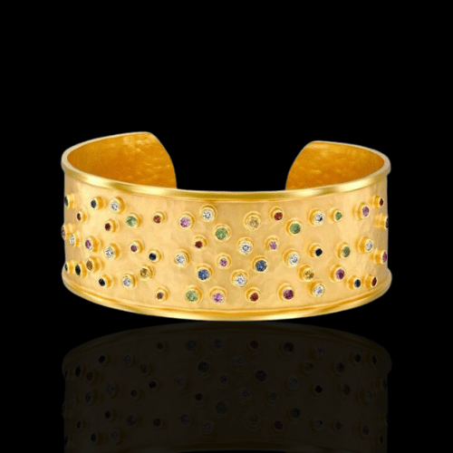 Gold cuff bracelet with colorful gemstones.