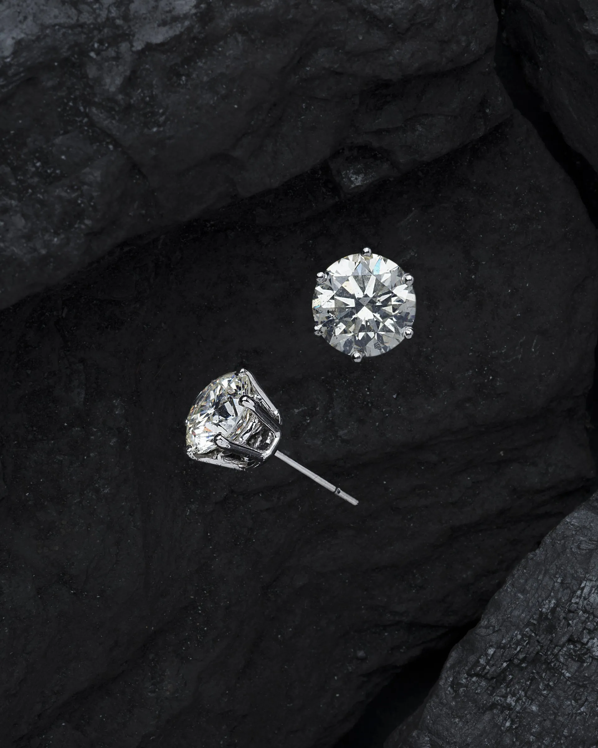 A pair of diamond earrings sitting on top of a rock.